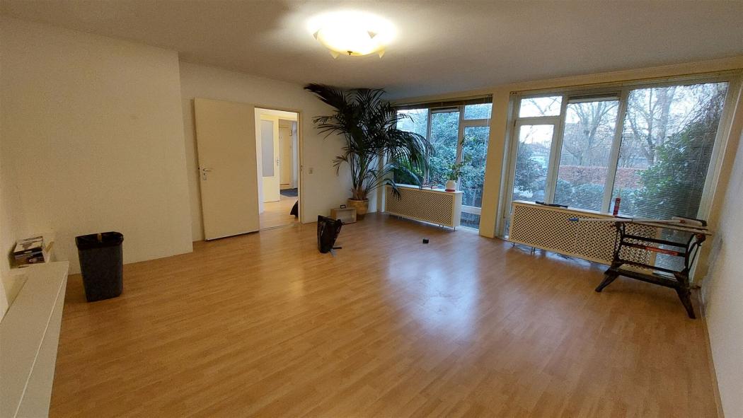 De woonkamer, grote ramen met vrij uitzicht. Laminaat op de vloer.